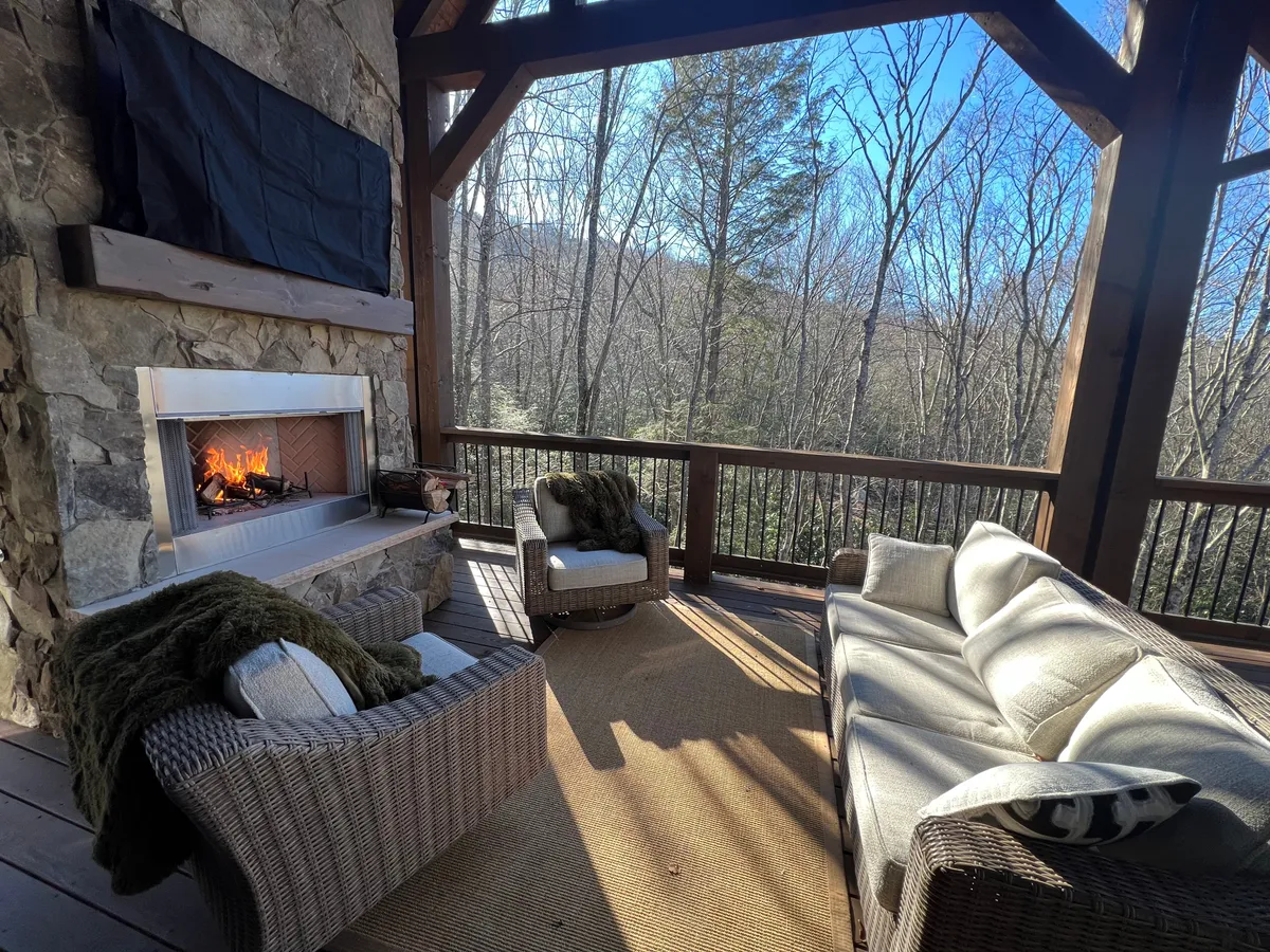 An inviting outdoor living space featuring a fireplace, comfortable seating, and lush natural surroundings. The setting is ideal for relaxing, socializing, or unwinding after outdoor adventures.