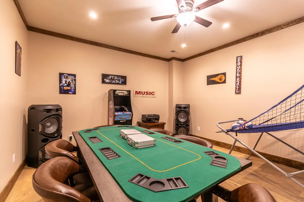 A fun and vibrant entertainment space showing a poker table, arcade machine, prominent speakers, and a music-themed sign. The atmosphere is lively, suggesting group play, gaming, and interactive music experiences.