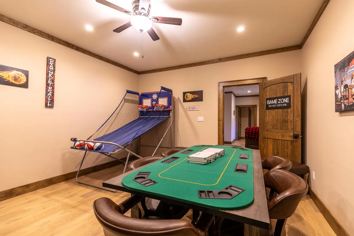 A lively game room scene with a poker/game table, basketball hoop, and vibrant artwork. This energetic space invites guests to play card games or challenge each other to a friendly round of basketball, perfect for multi-generational fun.