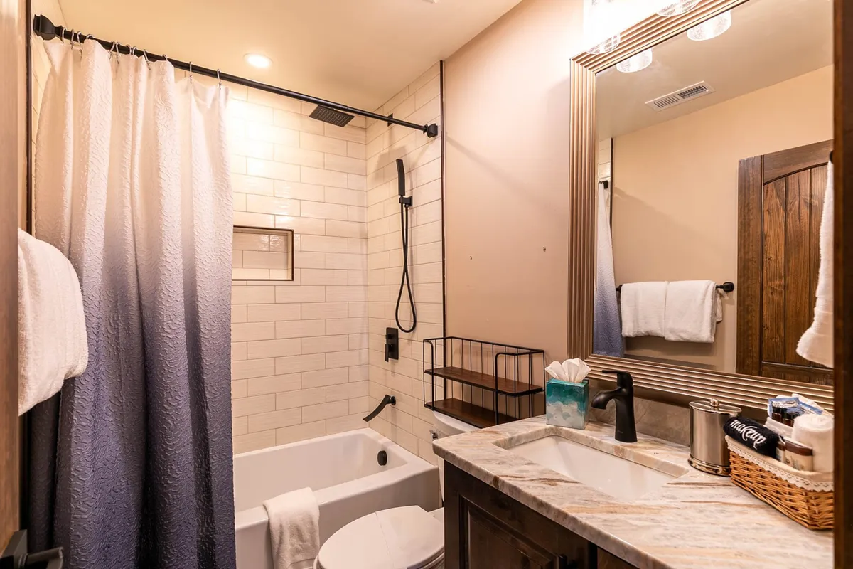 A stylish, spa-inspired bathroom featuring a spacious bathtub, modern shower area, a bright mirror, and a sleek sink. The clean design and plush linens evoke a sense of luxury and relaxation, ideal for indulging in self-care routines.