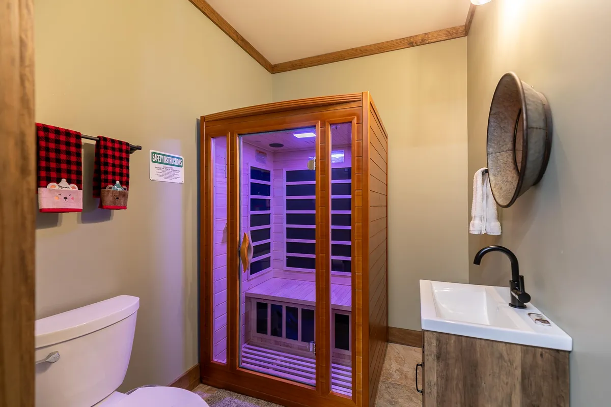 A serene wellness area featuring an infrared sauna, modern sink, toilet, and decorative towels. The tranquil mood and soothing design offer the perfect setting for relaxation and post-adventure recovery.